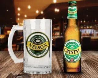 Shopper cervecero de vidrio personalizado con diseño 'Felicidades Papá Nelson' en verde y amarillo, junto a una botella de Cerveza Cristal fría sobre una mesa de madera rústica en un bar.