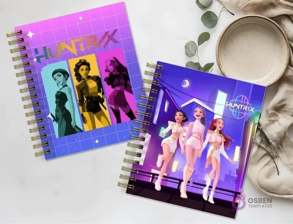 Dos agendas espiraladas 'HUNTRIX' con diseños de personajes femeninos de anime, sobre una superficie de mármol con una planta y un plato vacío.
