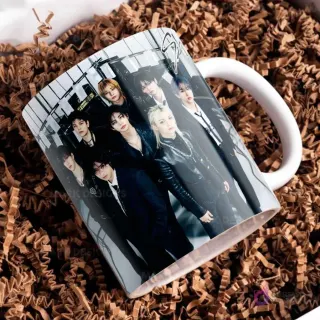 Taza blanca con el logo de Stray Kids y otra foto grupal, los miembros con atuendos oscuros de cuero, posando con estilo y seriedad.