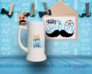 Shoperos blanco con diseño de sublimación 'HAPPY DAY DAD' en tonos verdes y azules con un dibujo de caja de regalo, sobre fondo azul decorativo.
