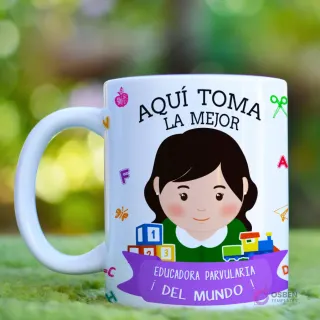 Taza blanca con diseño 'Aquí Toma La Mejor Educadora' presentando una ilustracion de educadora con cabello rojizo/cobrizo, rodeada de símbolos de educación infantil y un fondo verde desenfocado
