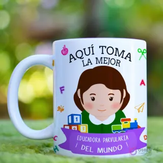 Taza blanca con diseño 'Aquí Toma La Mejor Educadora' con una caricatura de educadora de cabello castaño medio, elementos educativos vibrantes y un fondo natural verde desenfocado