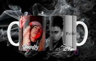 Dos tazas blancas sublimadas con imágenes de los artistas urbanos Standly y Pablo Chill-E, en un fondo oscuro con humo.