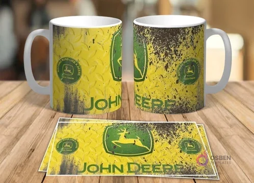 Dos tazas blancas de sublimación con diseño retro grunge del logo de John Deere sobre un fondo amarillo texturizado y dos plantillas planas del mismo diseño sobre una mesa de madera.