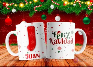 Taza sublimada con la letra J mayúscula en rojo y blanco con diseño de bota navideña, junto al nombre 'JUAN' y al reverso 'Feliz Navidad' con estrellas y copos de nieve.