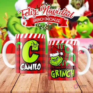 Taza de sublimación del Grinch temática de Navidad con la inicial 'C' y el nombre de ejemplo 'CAMILO', sobre fondo a cuadros rojo y blanco, junto a otra taza del Grinch con diseño navideño 'Esta Taza Pertenece al Grinch'. El fondo general muestra personajes del Grinch en Navidad.