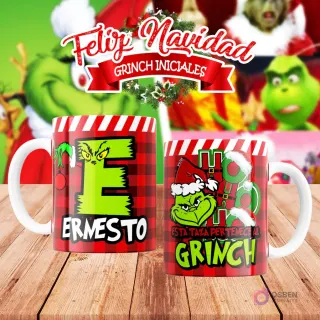 Taza de sublimación del Grinch temática de Navidad con la inicial 'E' y el nombre de ejemplo 'ERNESTO', sobre fondo a cuadros rojo y blanco, junto a otra taza del Grinch con diseño navideño 'Esta Taza Pertenece al Grinch'. El fondo general muestra personajes del Grinch en Navidad.
