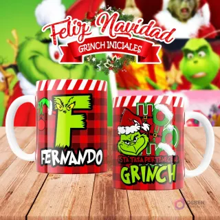 Taza de sublimación del Grinch temática de Navidad con la inicial 'F' y el nombre de ejemplo 'FERNANDO', sobre fondo a cuadros rojo y blanco, junto a otra taza del Grinch con diseño navideño 'Esta Taza Pertenece al Grinch'. El fondo general muestra personajes del Grinch en Navidad.