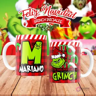 Taza de sublimación del Grinch temática de Navidad con la inicial 'M' y el nombre de ejemplo 'MARIANO', sobre fondo a cuadros rojo y blanco, junto a otra taza del Grinch con diseño navideño 'Esta Taza Pertenece al Grinch'. El fondo general muestra personajes del Grinch en Navidad.
