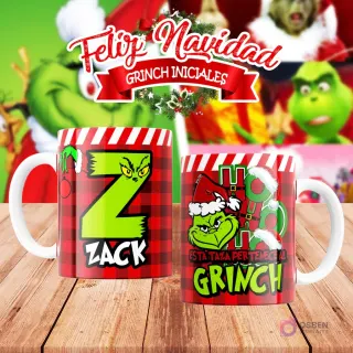 Taza de sublimación del Grinch temática de Navidad con la inicial 'Z' y el nombre de ejemplo 'ZACK', sobre fondo a cuadros rojo y blanco, junto a otra taza del Grinch con diseño navideño 'Esta Taza Pertenece al Grinch'. El fondo general muestra personajes del Grinch en Navidad.