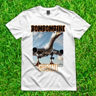 Camiseta blanca con diseño de 'Bombombini Gucini', un ganso híbrido con cuerpo de avión, alas y motores, despegando en un cielo azul.