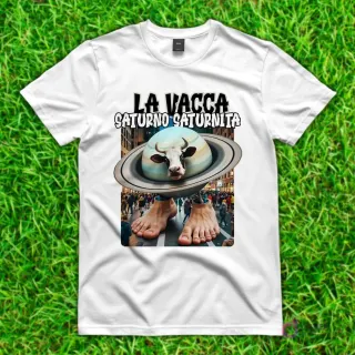 Camiseta blanca con diseño de 'La Vacca Saturno Saturnita', una vaca con la cabeza dentro de un planeta Saturno y pies humanos, caminando en una calle de ciudad.