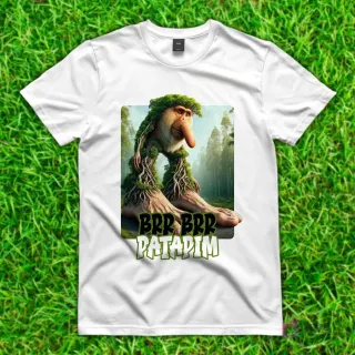 Camiseta blanca con diseño de 'Brr Brr Patadim', un mono narigudo con raíces y piernas gigantes de árbol, fusionado con un paisaje boscoso.