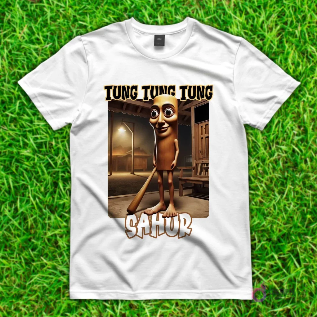 Camiseta blanca con diseño de 'Tung Tung Tung Sahur', una figura alargada y sonriente con ojos grandes, sosteniendo un bate en una habitación rústica.