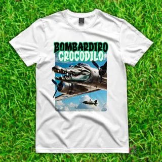 Camiseta blanca con diseño de 'Bombardiro Crocodilo', un cocodrilo con cuerpo de avión bombardero lanzando una bomba, volando en un cielo nublado.
