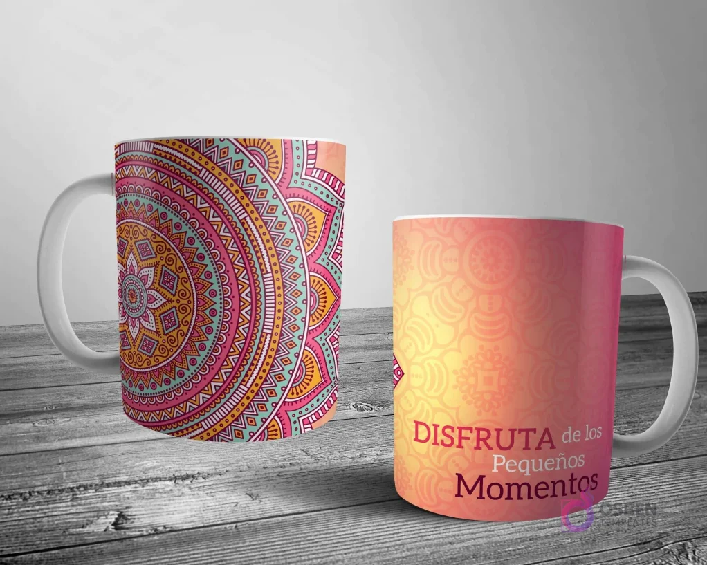 Dos tazas blancas con un diseño de mandala detallado. Una con un gran mandala rosa-teal-naranja y la otra con un patrón más sutil y la frase 'DISFRUTA de los Pequeños Momentos' en tonos cálidos.