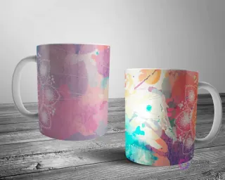 Dos tazas blancas con un diseño de mandala de contorno blanco parcialmente oculto por salpicaduras abstractas de acuarela en rosa, morado, naranja y azul.