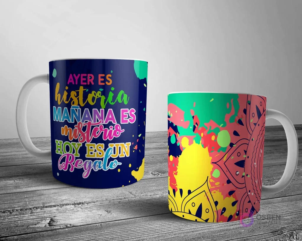 Dos tazas blancas con un diseño de mandala abstracto e inspirador. Una con la cita 'AYER ES historia MAÑANA ES misterio HOY ES UN regalo' y la otra con un mandala colorido sobre salpicaduras de pintura.