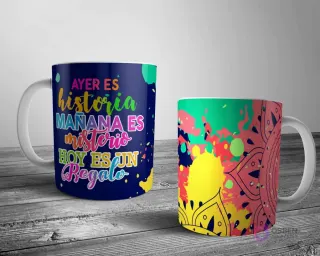 Dos tazas blancas con un diseño de mandala abstracto e inspirador. Una con la cita 'AYER ES historia MAÑANA ES misterio HOY ES UN regalo' y la otra con un mandala colorido sobre salpicaduras de pintura.