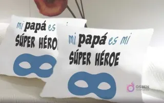 Cojines de sublimación blancos con el diseño 'Mi papá es mi SÚPER HÉROE' en tipografía negra y azul, acompañado de una máscara de superhéroe azul, perfecto para niños.