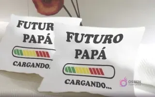 Dos cojines blancos con el diseño 'FUTURO PAPÁ CARGANDO...' en negro, acompañado de una barra de progreso que va de verde a rojo, un regalo divertido para futuros padres.