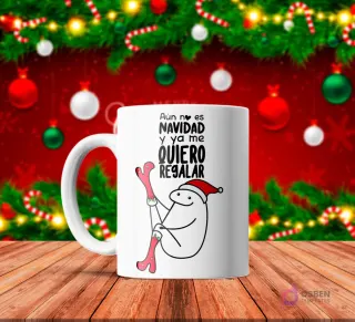 Taza de sublimación blanca con Flork con gorro de Santa intentando ponerse medias navideñas, texto 'Aún no es NAVIDAD y ya me QUIERO REGALAR' con fondo navideño rojo.