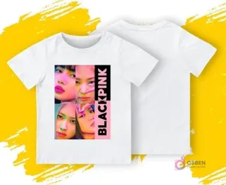 Una polera blanca con un diseño frontal de cuatro retratos en primer plano de las integrantes de Blackpink con un logo vertical 'BLACKPINK'. Se muestra la parte delantera y trasera de la polera sobre un fondo amarillo y gris.