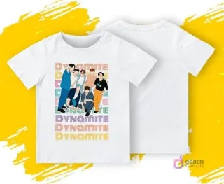 Una polera blanca con una ilustración frontal de los miembros de BTS de la era 'Dynamite' y el texto 'DYNAMITE' repetido. Se muestra la parte delantera y trasera de la polera sobre un fondo amarillo y gris.