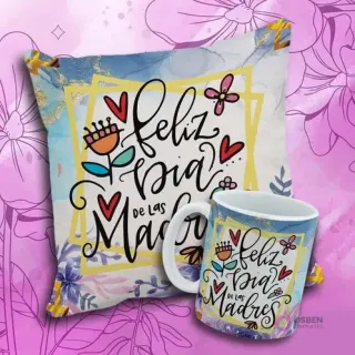 Cojín y taza con el diseño 'Feliz Día de Las Madres', flores coloridas, mariposa y marco dorado sobre fondo azul.