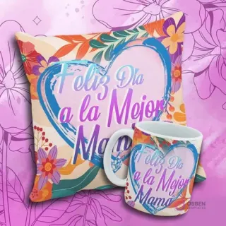 Cojín y taza con el mensaje 'Feliz Día a la Mejor Mama' en un corazón artístico azul y rosa con flores abstractas.