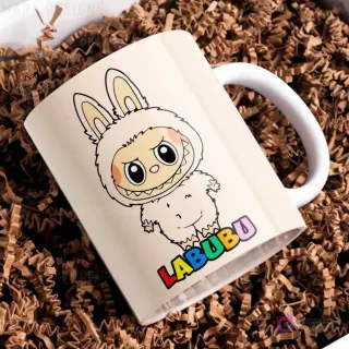 Taza de cerámica beige con diseño del personaje Labubu de traje peludo beige, con el nombre Labubu en letras coloridas, sobre papel picado marrón.