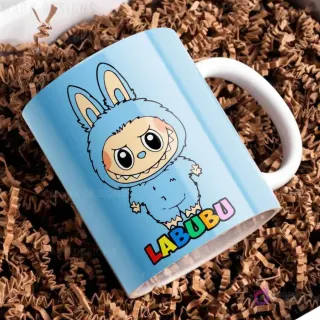 Taza de cerámica azul claro con diseño del personaje Labubu de traje peludo azul, con el nombre Labubu en letras coloridas, sobre papel picado marrón.