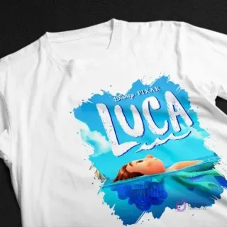 Polera blanca con diseño sublimado de Luca de Disney Pixar en forma humana, parcialmente sumergido en el agua, sobre un fondo azul estilo acuarela.