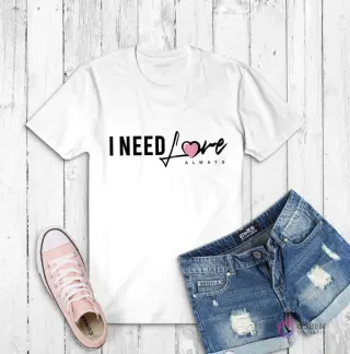 Polera blanca con la frase 'I NEED LOVE ALWAYS' en tipografía moderna con un corazón rosa