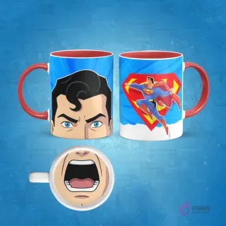 Taza de sublimación con diseño animado de Superman volando y un primer plano de su rostro furioso. En la base de la taza, una boca abierta. El asa de la taza es roja.