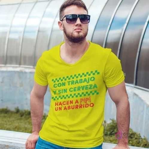 Hombre con camiseta amarilla sublimada con la frase divertida 'CON TRABAJO Y SIN CERVEZA HACEN A PAPÁ UN ABURRIDO', mostrando la versatilidad de los diseños.
