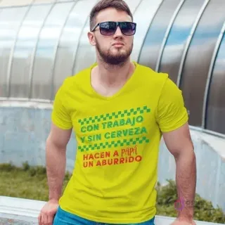 Hombre con gafas de sol usando una polera amarilla con el diseño 'CON TRABAJO Y SIN CERVEZA HACEN A PAPÁ UN ABURRIDO' en colores verde y rojo.