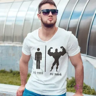 Hombre con gafas de sol usando una polera blanca con el diseño 'TÚ PAPÁ' (figura delgada) y 'MI PAPÁ' (figura musculosa), un diseño cómico para el Día del Padre.