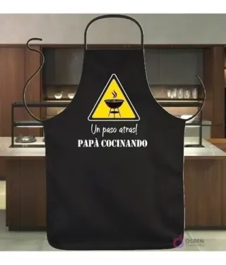 Delantal negro sublimado con diseño vectorial de humor 'Un paso atrás! Papá Cocinando' y señal de advertencia de parrilla.