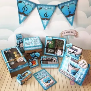 Amplia variedad de cajas y decoraciones de papel para Candy Bar Día del Padre, con diseños de bigotes y corazones en tonos azules y marrones sobre fondo de madera.