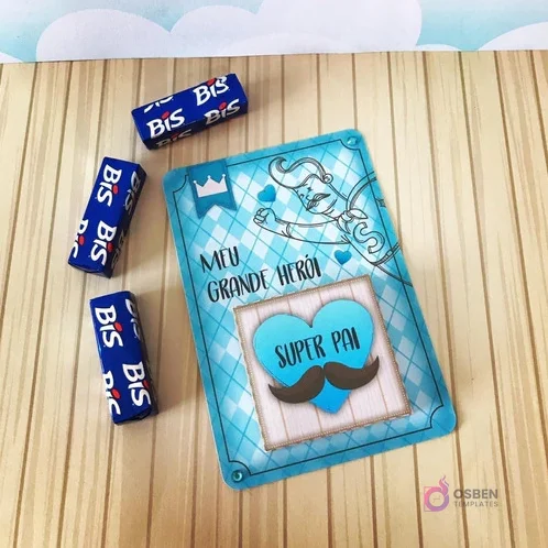 Tarjeta decorativa 'Meu Grande Herói Super Pai' con diseño de bigotes y coronas, junto a tres chocolates Bis envueltos, ideal para complementar un Candy Bar del Día del Padre.