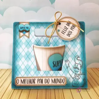 Caja de papel con diseño azul a cuadros y un recorte para una taza de café, con el texto 'O Melhor Pai do Mundo' y una etiqueta 'Feliz Dia dos Pais', ideal para regalo.