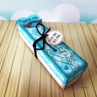 Caja alargada pequeña de papel con diseño azul a cuadros, ideal para dulces o pequeños detalles, decorada con un lazo negro y etiqueta 'Feliz Día dos Pais'.