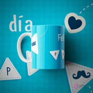Taza de sublimación azul claro con patrones geométricos y pegatinas con las letras 'P A P' un corazón, una corona y un bigote, sobre un fondo azul vibrante con la palabra 'día'.