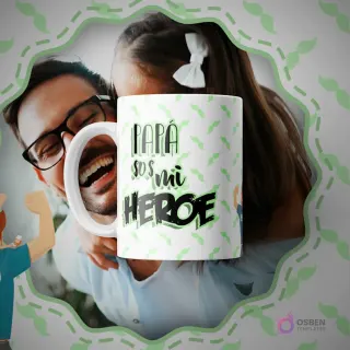 Taza de sublimación blanca con un patrón de bigotes verdes y la frase 'PAPÁ SOS MI HEROE' en letras verdes y negras, sobre un fondo de un padre sonriendo con su hija.