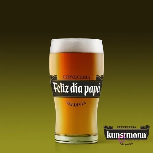 Shopero de cerveza con etiqueta personalizada 'Feliz día papá' al estilo Cervecería Kunstmann, sobre fondo verde oscuro.