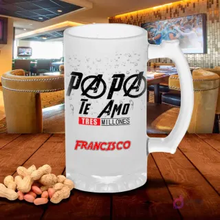 Chopp de vidrio esmerilado con diseño 'Papá Te Amo Tres Millones' con tipografía estilo Vengadores, sobre mesa de madera y cacahuetes, fondo de bar. Plantilla sublimación Padres.
