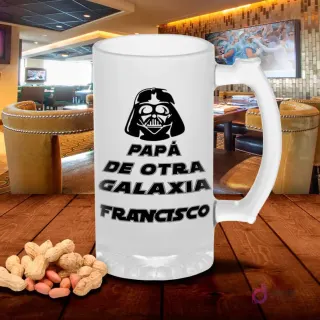Shoper de vidrio esmerilado con diseño 'Papá de otra galaxia' y casco de Darth Vader, sobre mesa de madera con cacahuetes, fondo de bar. Plantilla Star Wars Día del Padre.