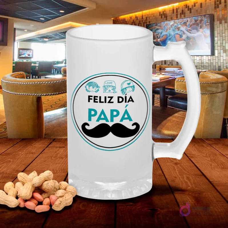 Chopp de vidrio esmerilado con diseño circular 'Feliz Día Papá' en tonos turquesa con bigote y pequeñas figuras de niños, sobre mesa de madera con cacahuetes, fondo de bar. Plantilla familiar Día del Padre.