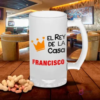 Chopero de vidrio esmerilado con diseño 'El Rey de la Casa FRANCISCO' con corona naranja, sobre mesa de madera con cacahuetes, fondo de bar. Plantilla sublimación Rey de la Casa.